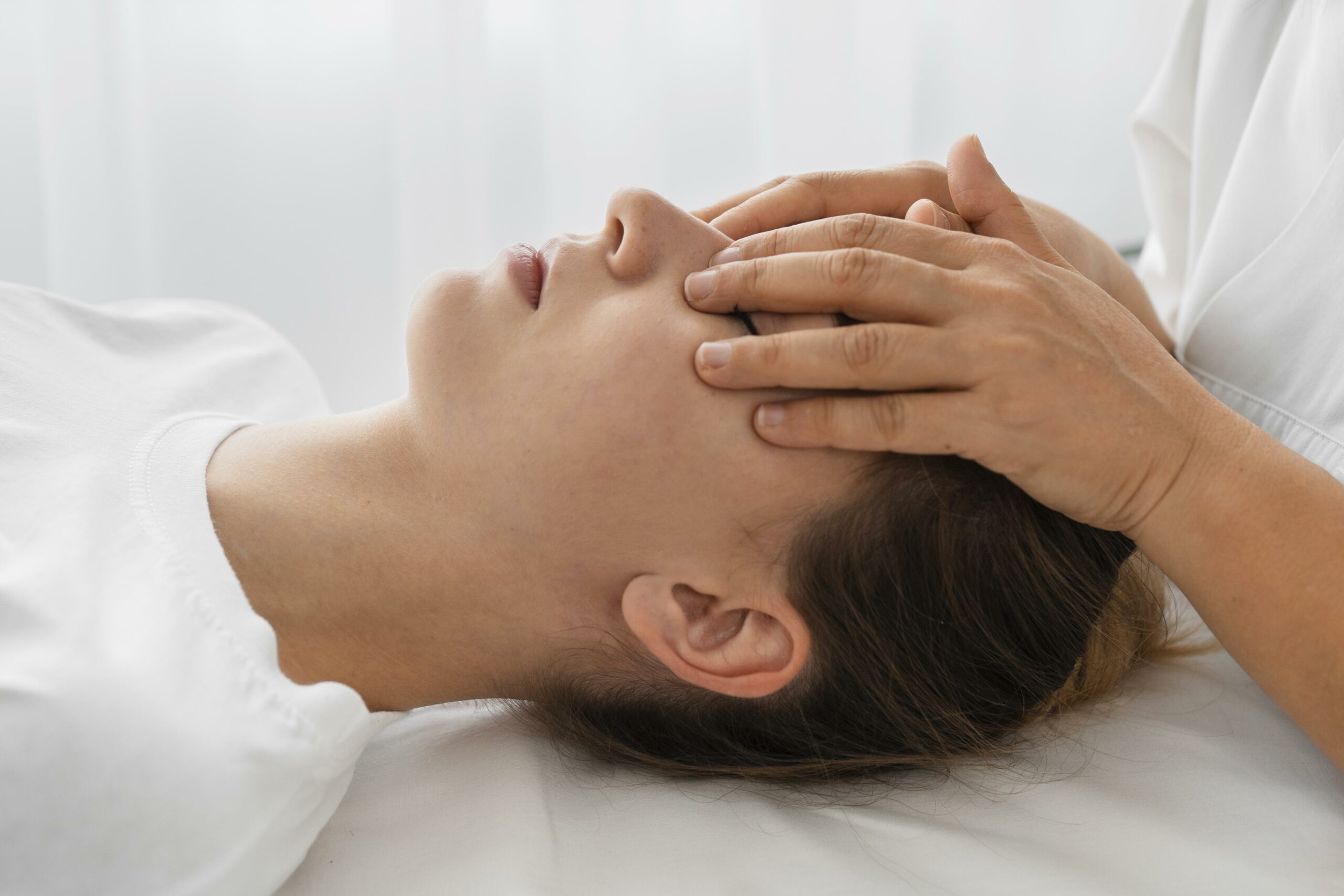 female-osteopathist-treating-patient-by-massaging-her-face